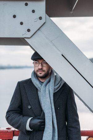 handsome adult man standing on bridge and covering head with its construction