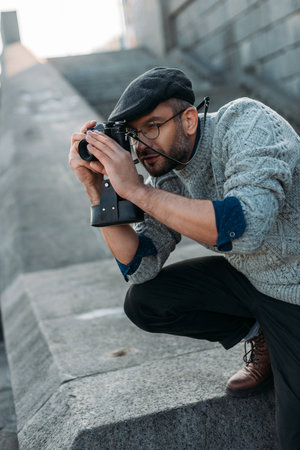 handsome adult  man taking photo with vintage film camera outdoorsの写真素材