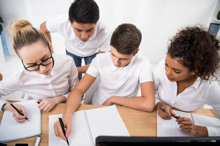 young students writing something in notebooksの写真素材