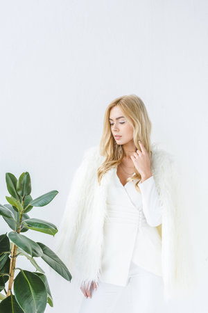 stylish attractive woman in fur coat posing at ficus plantの写真素材