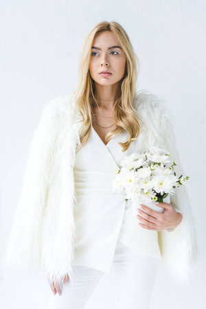 beautiful stylish woman in fur coat holding white flowers, isolated on whiteの写真素材