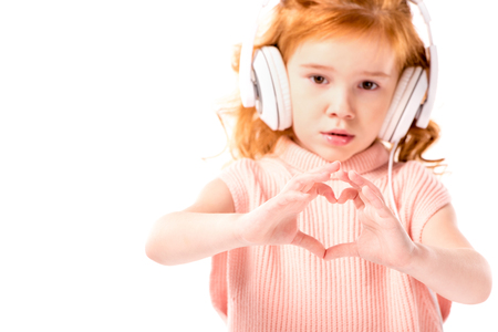 red hair kid in headphones showing heart with fingers isolated on whiteの写真素材