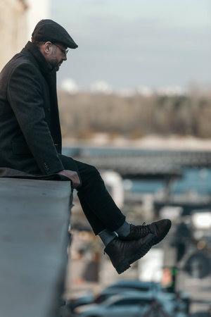 lonely middle aged man sitting on roof of buildingの写真素材