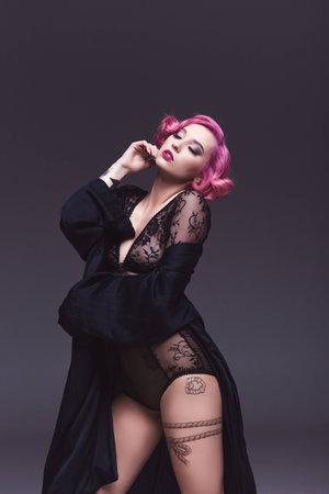 seductive tattoed pin up girl in transparent lingerie infront of grey backgroundの写真素材