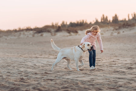 happy child running with labrador dog on sandy beach