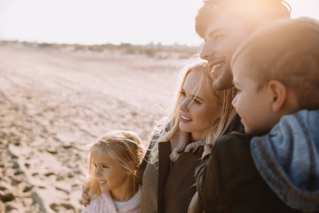 happy family hugging together on seashore in autumnの写真素材