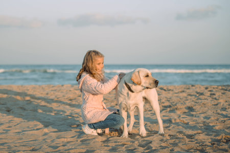 kid walking with labrador dog on beach at sea