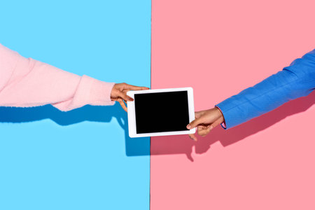 cropped shot of african american couple holding tablet against pink and blue wallの写真素材