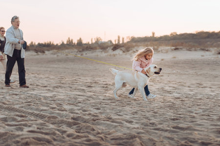 grandparents and granddaughter walking with dog on sandy beach