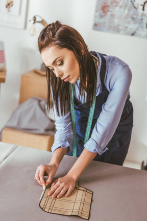 beautiful seamstress making pattern with piece of chalk on fabricの写真素材