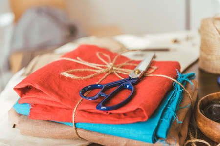 stack of colored fabric and scissors on table in working roomの写真素材