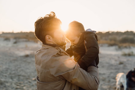 father hugging his son on seashore with backlitの写真素材