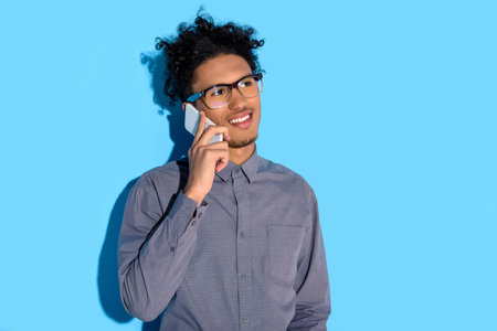 Young african amercian businessman talking on phone on blue background