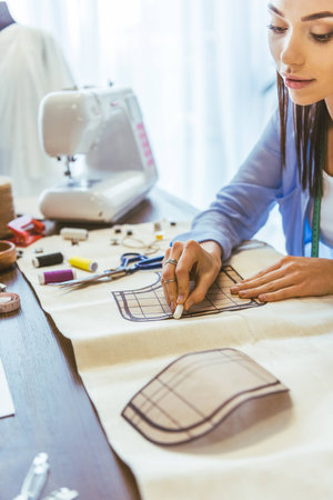 attractive seamstress marking pattern with piece of chalk
