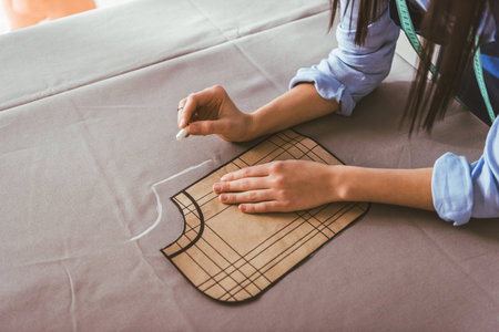 cropped image of seamstress making pattern with piece of chalk on fabric