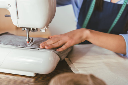 cropped image of seamstress sewing with sewing machine