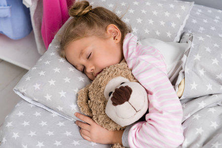 adorable little kid sleeping with teddy bearの写真素材