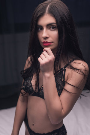 sensual girl in sexy lingerie posing in dark bedroomの写真素材