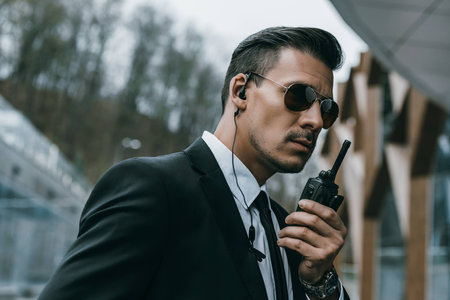 serious handsome security guard talking by portable radioの写真素材