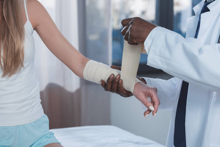 Cropped image of african american doctor bandaging patient hand