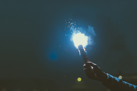 cropped view of male hand with smoke bomb at nightの写真素材