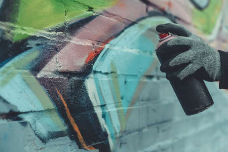 cropped view of man painting colorful graffiti on wall