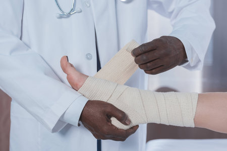 Cropped image of african american doctor bandaging patient legの写真素材