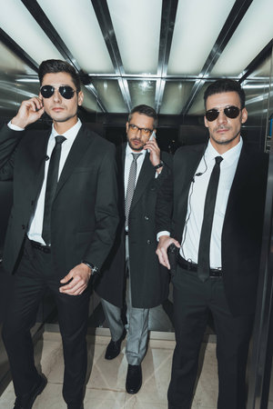 businessman talking by smartphone and going with bodyguards