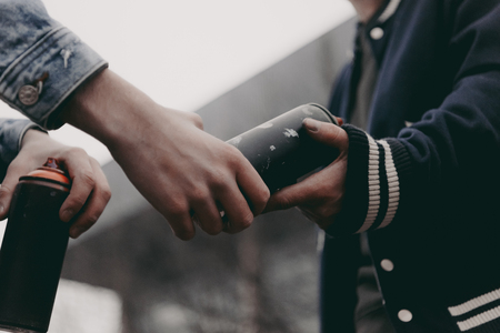 cropped view of street artists holding cans with spray paintの写真素材