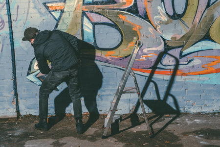 street artist painting colorful graffiti on wall of buildingの写真素材
