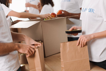 cropped shot of group of volunteers packing food for charityの写真素材