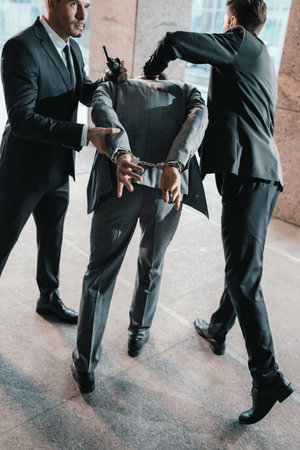 Cropped image of security guards arresting offenderの写真素材