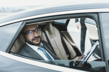 businessman sitting in a car with newspaper and looking awayの写真素材