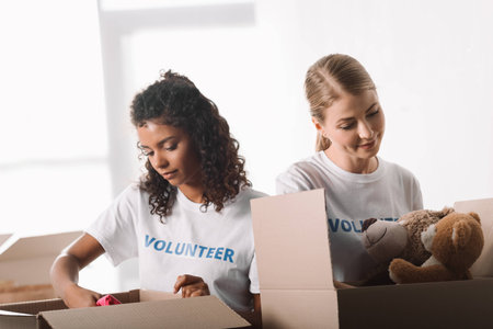 beautiful young female volunteers packing toys for charityの写真素材