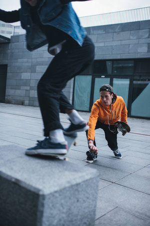 skateboarder taking photo of his partner doing trickの写真素材