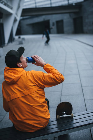 skateboarder drinking water and relaxing on bench after rideの写真素材