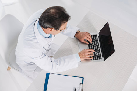 overhead view of doctor using laptop at working placeの写真素材