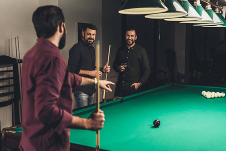 company of successful men beside gambling pool table at barの写真素材