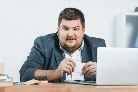 fat businessman in suit working with smartphone and laptop at workplaceの写真素材