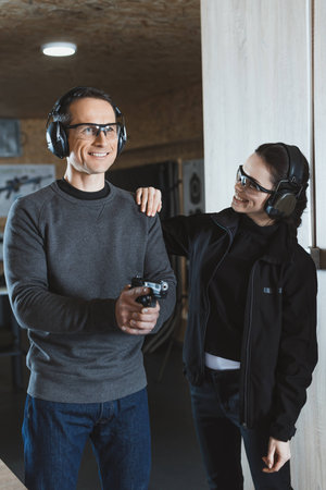smiling shooting instructor supporting client in shooting range