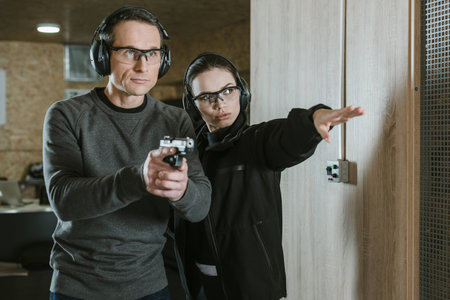 female instructor showing where shoot to client in shooting rangeの写真素材
