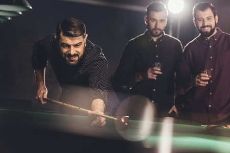 successful man playing in pool at bar with friends