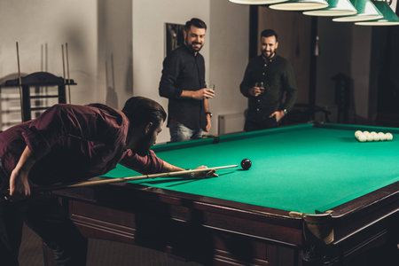 successful man playing in pool at bar with friends