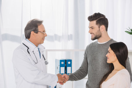 doctor and smiling patient shaking handsの写真素材