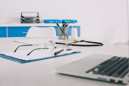 clipboard with glasses and laptop at wooden table in clinicの写真素材