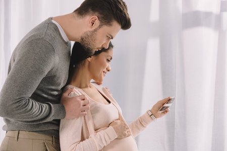 pregnant woman and husband looking at photo of ultrasound diagnosticsの写真素材
