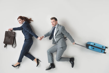 overhead view of business colleagues with baggage holding hands isolated on greyの写真素材