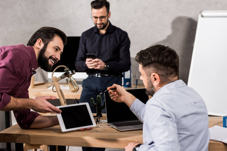 smiling businessman showing something on tablet to colleagues