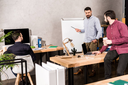 businessman describing something to colleagues at flipchart in office