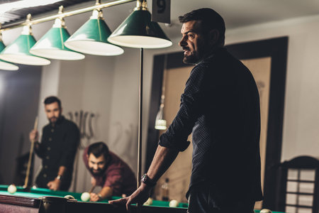 company of successful handsome men playing in pool at barの写真素材